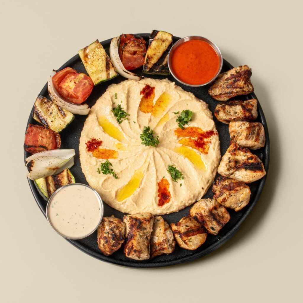 A hummus platter with grilled meat and tahini