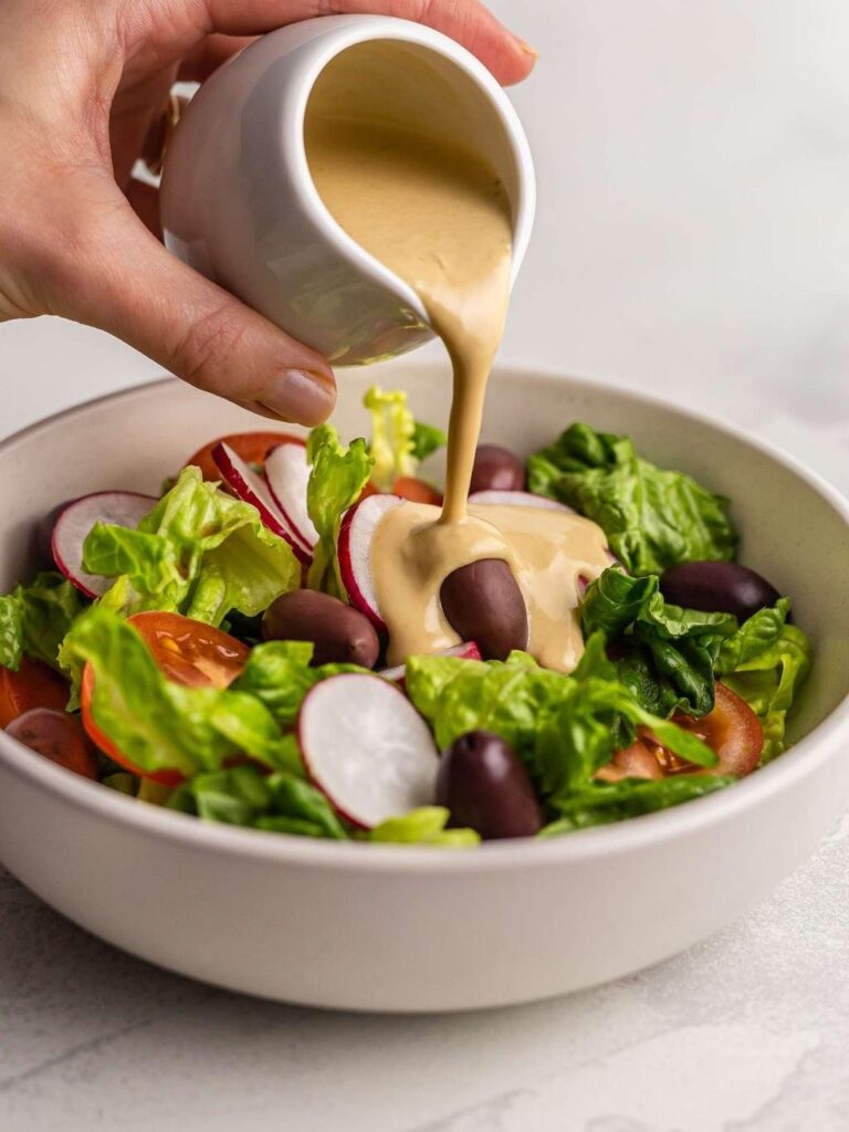 Tahini sauce poured over a fresh salad